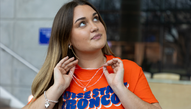 One person putting a necklace on another inside the Bronco Shop