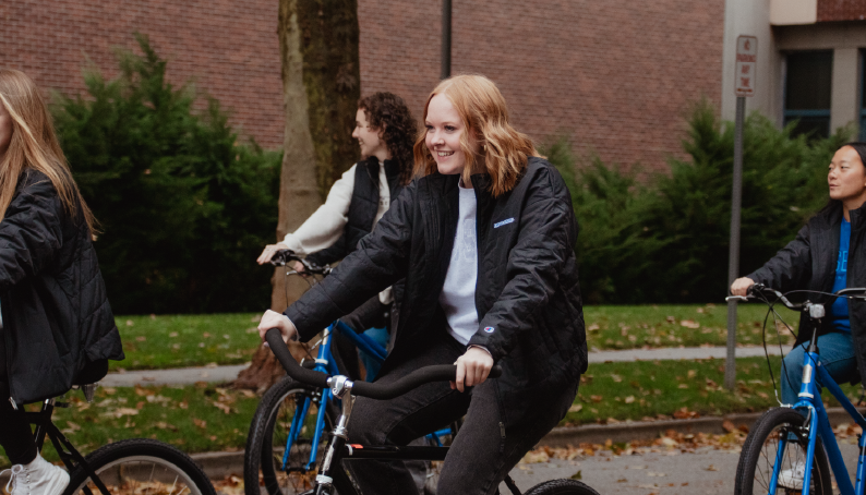 A person riding a bike outdoors wearing a black jacket.