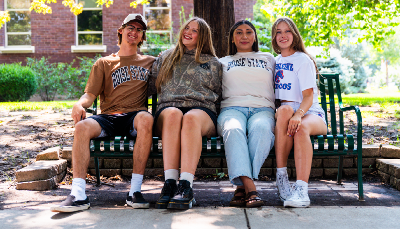 Boise State students wearing apparel from the Camo Collection while sitting together on campus