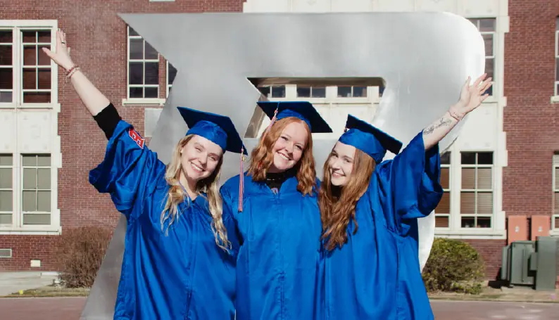 Three women in graduation regalia.